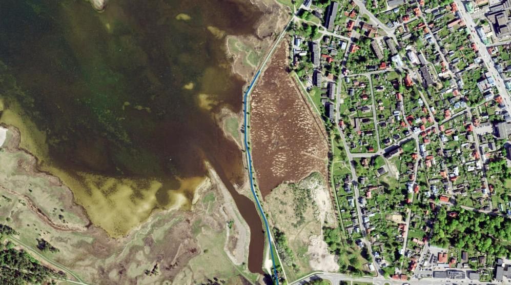Aerial image of a bay shore with a detected barrier line drawn in blue between the water and a town